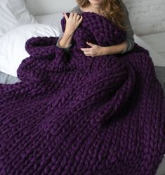 a woman wrapped up in a purple blanket