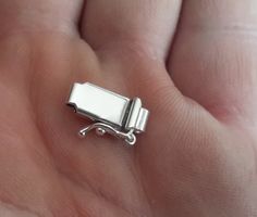 a small silver object sitting on top of someone's hand