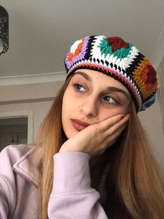 a woman with long hair wearing a colorful crochet hat and looking at the camera