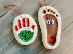 two hand and foot ornaments on a wooden floor with red string hanging from the top