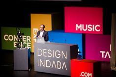 a man standing at a podium in front of colorful blocks with the words design india on them