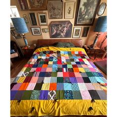 a bed covered in a multi colored quilt next to pictures on the wall above it