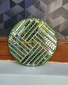 a green plate sitting on top of a window sill next to a patterned wall