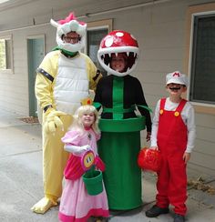 three people in costumes standing next to each other on the sidewalk near a trash can