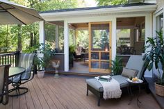 a patio with chairs, tables and an umbrella on the deck area next to it