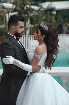 a man and woman dressed in formal wear standing next to each other near a pool