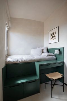 a bed sitting on top of a green shelf next to a window in a bedroom