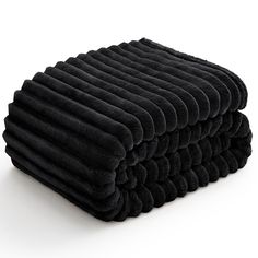 two black towels stacked on top of each other in front of a white background,