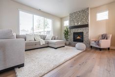 a living room with a couch, chair and fire place in the corner on top of a hard wood floor