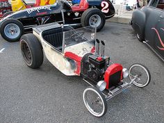 an old model car is parked in a parking lot with other antique cars behind it