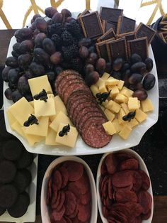 an assortment of cheeses, crackers and grapes on a platter with chocolate bars