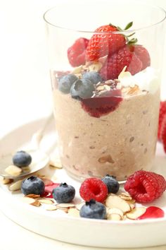 a dessert with berries, almonds and blueberries in a glass on a plate