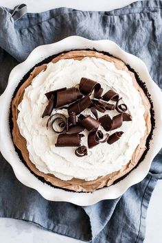 there is a pie with white frosting and chocolate pieces on the top, sitting on a blue napkin