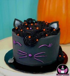 a black cat cake with purple icing and orange sprinkles on top