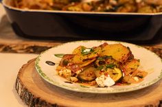 a white plate topped with food next to a casserole dish filled with vegetables