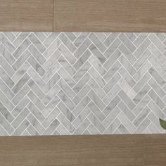 white marble herringbone tile on a wood floor