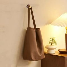 a brown purse hanging on the wall next to a table with a lamp in it