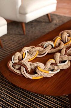 a wooden table topped with a brown and yellow chain necklace on top of it's side