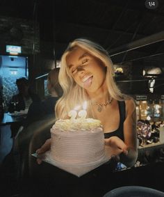 a woman holding a birthday cake with lit candles