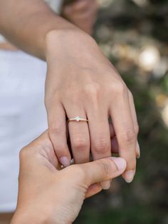 two people holding hands while one holds the other's hand with an engagement ring