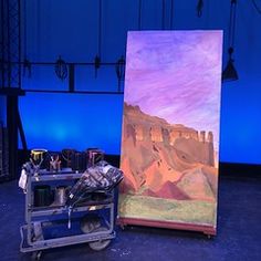 an easel sitting on top of a stage with a painting in front of it