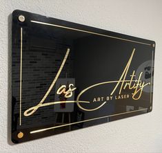 a black and gold sign hanging from the side of a wall next to a white wall