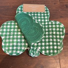 a green and white checkered heart shaped pot holder on a wooden floor with a card