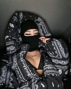 a woman wearing a black bandana covering her face with a mask on top of her head