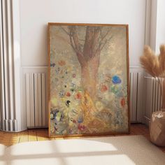 a painting sitting on top of a hard wood floor next to a vase with flowers