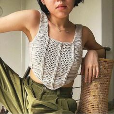 a woman sitting on top of a chair next to a wicker basket and looking at the camera