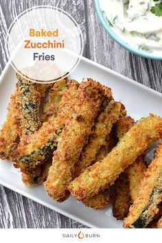 baked zucchini fries on a white plate next to a bowl of ranch dressing