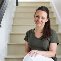 a woman sitting on the stairs smiling at the camera