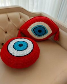 two crocheted pillows with an evil eye on the top and bottom one is red