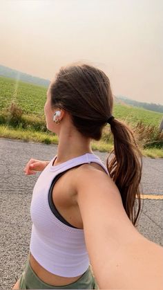 a woman is walking down the street with an earplug in her ears and wearing a white tank top