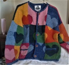 a multicolored cardigan sweater hanging on a clothes hanger in a bedroom