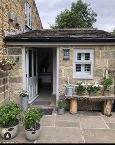 a stone house with potted plants outside