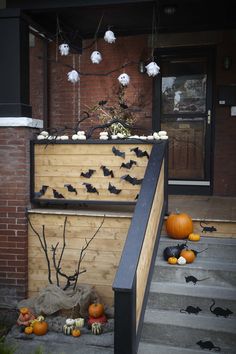 halloween decorations on the front steps of a house with bats and pumpkins scattered around