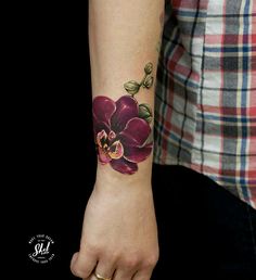 a woman's arm with a purple flower tattoo on the left side of her wrist