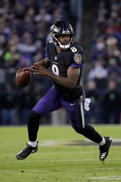 a football player holding a ball on top of a field with people in the background