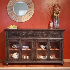 a wooden cabinet with glass doors in front of a red wall