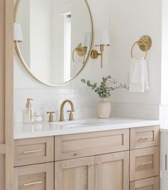 a bathroom with two sinks and a large round mirror above the sink, along with gold faucets