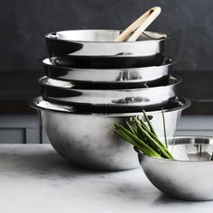 a stack of stainless steel bowls with wooden spoons