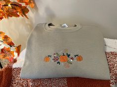 Fall embroidered sweatshirt- pumpkin, mushroom, leaves! This design is on our Khaki colored sweatshirt! Jerzees Sweatshirt- Unisex Sizing 50% Cotton/ 50% Polyester so it may shrink a little in the dryer but we find them to be true to size! Each sweatshirt comes with a layer of stabilizer attached to the inside of the sweatshirt  If you have any questions please message us! Thank you for supporting our small business. Fall Sweatshirt With Embroidered Graphics, Fall Crew Neck Sweatshirt With Machine Embroidery, Fall Crew Neck Tops With Machine Embroidery, Cotton Sweatshirt With Machine Embroidery For Fall, Casual Fall Sweatshirt With Machine Embroidery, Casual Machine Embroidered Sweatshirt For Fall, Casual Fall Sweater With Custom Embroidery, Fall Crew Neck Sweatshirt With Custom Embroidery, Fall Long Sleeve Sweatshirt With Custom Embroidery