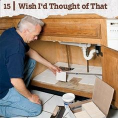 an older man is sitting on the floor in front of his kitchen sink and fixing it