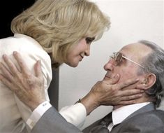 an older man and woman are touching each other's foreheads while they look at each other