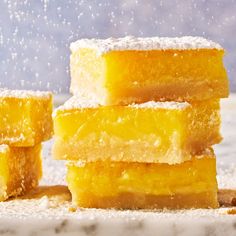 several pieces of yellow cake sitting on top of a white countertop covered in powdered sugar