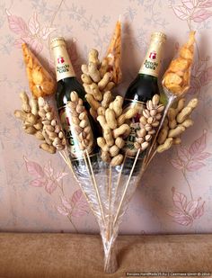 two bottles of champagne and some nuts on a table with pink wallpaper behind it