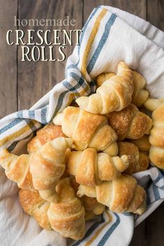 croissant rolls piled on top of each other in a white bowl with blue and yellow striped napkin