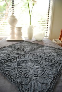 a crocheted doily sitting on top of a table next to a vase with flowers