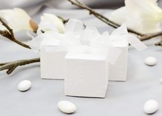 two small white boxes sitting on top of a table next to some flowers and eggs